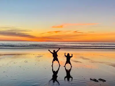 two people jumping on the beach at sunset at Sea View Villas in Duklei in Budva