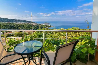 a balcony with a table and chairs and the ocean at Open Sky Apartments in Utjeha