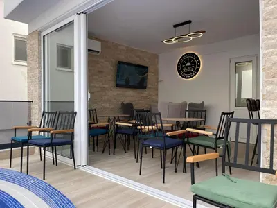 a restaurant with chairs and tables and a clock on the wall at Relax Apartmani in Sutomore