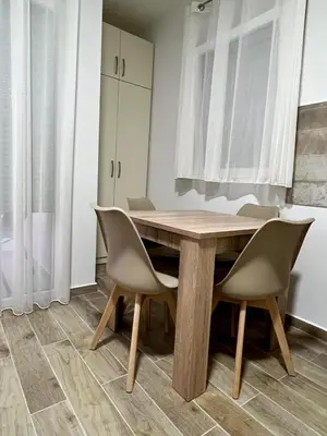 a dining room with a wooden table and chairs at Relax Apartmani in Sutomore