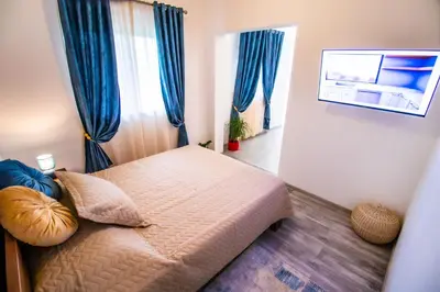 a small bedroom with a bed with blue curtains at Simo apartments airport Podgorica in Podgorica
