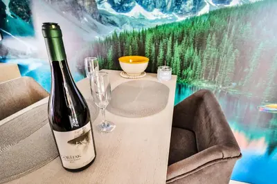 a bottle of wine sitting on a table with a glass at Simo apartments airport Podgorica in Podgorica