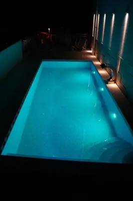 a swimming pool with blue water in a dark room at Garni Hotel Larimar in Budva