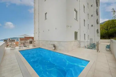a swimming pool in front of a building at Garni Hotel Larimar in Budva