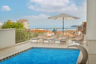 a swimming pool with chairs and an umbrella on a balcony at Garni Hotel Larimar in Budva