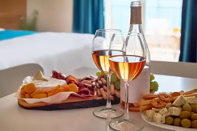 a table with two glasses of wine and a basket of food at Garni Hotel Larimar in Budva