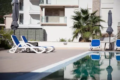 a swimming pool with chairs and umbrellas next to a building at Spa Resort Bečići in Budva