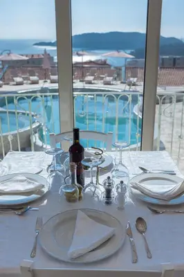 a table with a white table cloth and plates and silverware at Spa Resort Bečići in Budva
