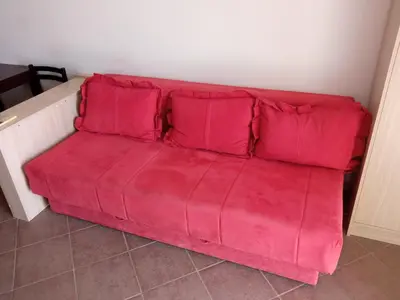 a red couch with red pillows in a room at Apartman Odisej in Petrovac na Moru