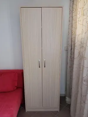 a white cabinet with two doors next to a red couch at Apartman Odisej in Petrovac na Moru