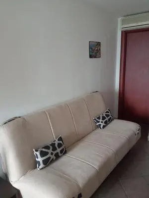 a couch with three pillows on it in a living room at Apartman Odisej in Petrovac na Moru