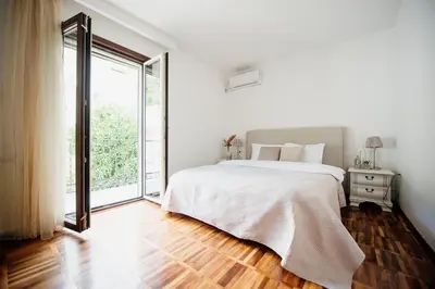a white bedroom with a bed and a large window at Villa Danigo in Budva