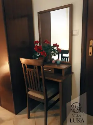 a desk with a mirror and a chair with flowers on it at Apartments Villa Luka in Sveti Stefan