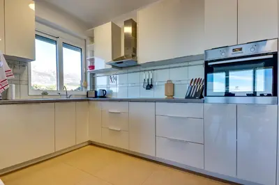 a large white kitchen with white cabinets and appliances at Montenegro Apartments Utjeha in Utjeha