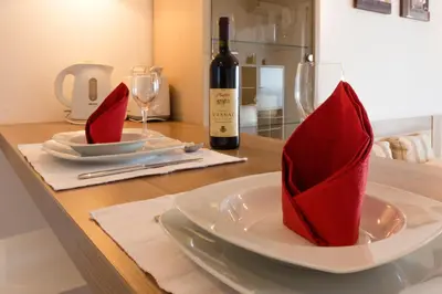 a table with a plate with red napkins and a bottle of wine at Montenegro Apartments Utjeha in Utjeha