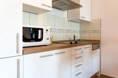 a kitchen with white cabinets and a microwave at Montenegro Apartments Utjeha in Utjeha