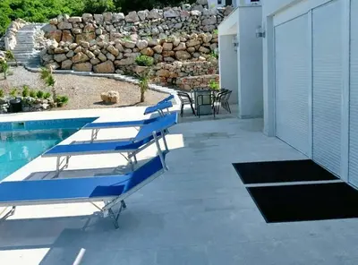 a patio with blue lounge chairs next to a swimming pool at Charming Villa with Pool, Sea View in Zagora in Zagora