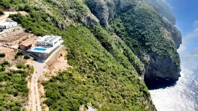 a building on the side of a mountain next to the water at Charming Villa with Pool, Sea View in Zagora in Zagora