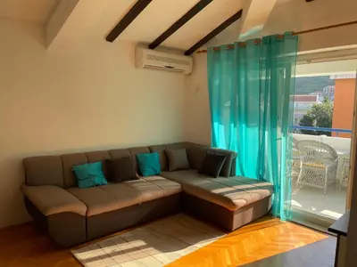 a couch sitting in a living room with a window at Adok stan in Budva