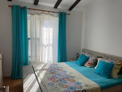a bedroom with a large bed with blue curtains at Adok stan in Budva