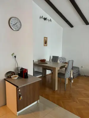a dining room with a table and a clock on the wall at Adok stan in Budva