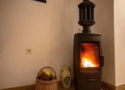 a wood stove with a fire in a room at Уютная квартира в тени старого дуба in Becici