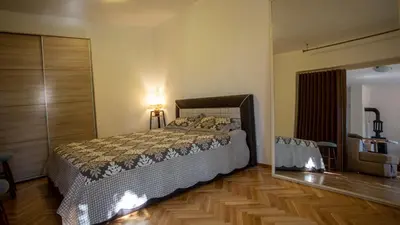 a bedroom with a bed and a wooden floor at Уютная квартира в тени старого дуба in Becici