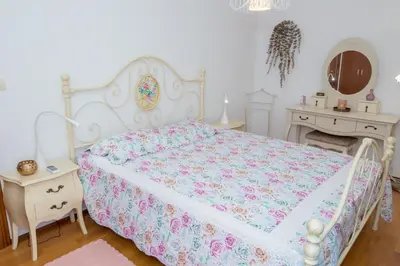 a bedroom with a bed and two tables and a mirror at Apartment Elena Petrovac in Petrovac na Moru