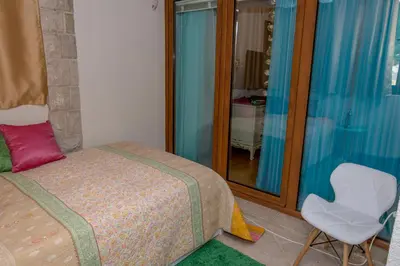 a bedroom with a bed and a chair and a mirror at Apartment Elena Petrovac in Petrovac na Moru