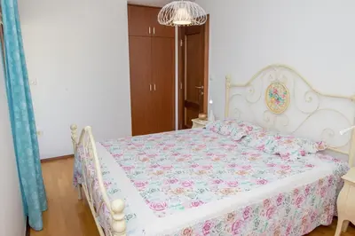 a bedroom with a white bed with a floral bedspread at Apartment Elena Petrovac in Petrovac na Moru