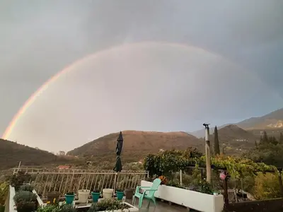 a rainbow over a garden with chairs and tables at Family Stone house with magical Sea View in Kaluđerac