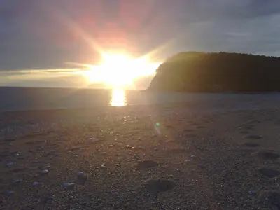 a sunset on a beach with the sun setting at Family Stone house with magical Sea View in Kaluđerac