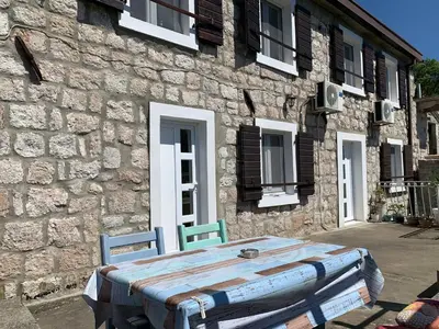 a table and two chairs in front of a stone building at Family Stone house with magical Sea View in Kaluđerac