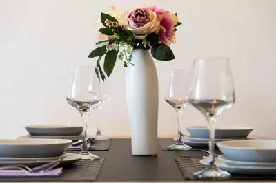 a table with wine glasses and a vase with a flower at Apart Compliment in Podgorica