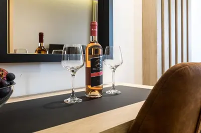 a bottle of wine sitting on a table with two wine glasses at Apart Compliment in Podgorica