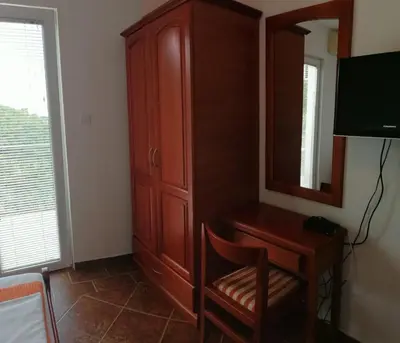 a bedroom with a wooden cabinet and a mirror at Apartments Mitrović Podličak in Sveti Stefan