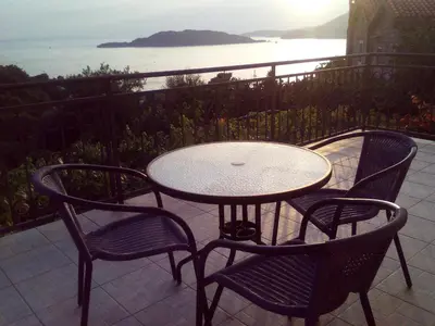 a table and four chairs on a patio with the ocean at Apartments Mitrović Podličak in Sveti Stefan
