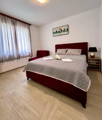 a bedroom with a large bed and a red chair at Guesthouse Civovic in Bar