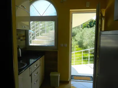 a kitchen with two windows and a view of a balcony at President Bungalows and Apartments in Utjeha
