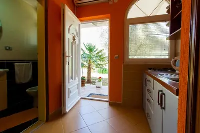 an orange kitchen with an open door to a bathroom at President Bungalows and Apartments in Utjeha