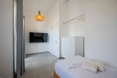 a white bedroom with a bed and a tv at President Bungalows and Apartments in Utjeha