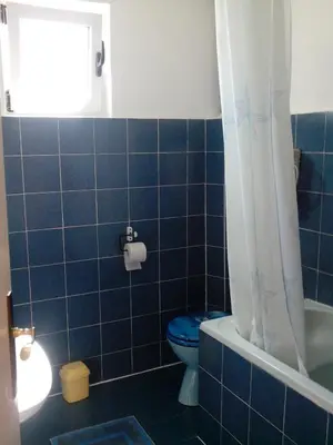 a blue tiled bathroom with a toilet and a window at Studios Velika Plaža in Ulcinj