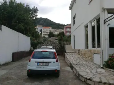 a white car parked in a parking lot next to a building at Guest House Mudresa in Budva