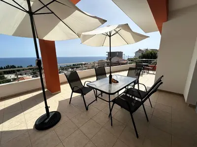 a table and chairs with umbrellas on a balcony at Apartments Olga in Ulcinj