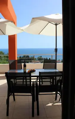 a table and chairs with an umbrella on a balcony at Apartments Olga in Ulcinj