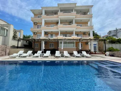 a hotel with a swimming pool in front of a building at Queen Kodre Apartments in Ulcinj
