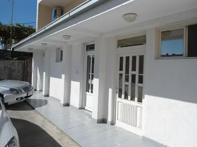 a white house with a car parked next to it at Apartments Jankovic in Podgorica