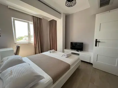 a white bedroom with a bed and a television at Bella Vista B&B in Ulcinj