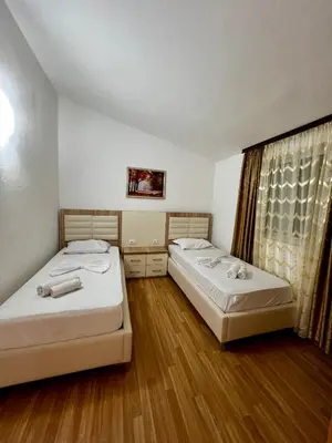 two beds in a room with wooden floors and a window at Apartments Rudaj in Ulcinj