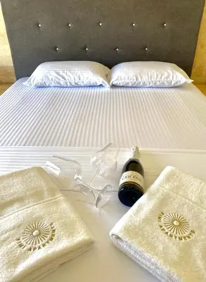 a bed with a bottle of wine and glasses on it at Fimi Apartments in Ulcinj